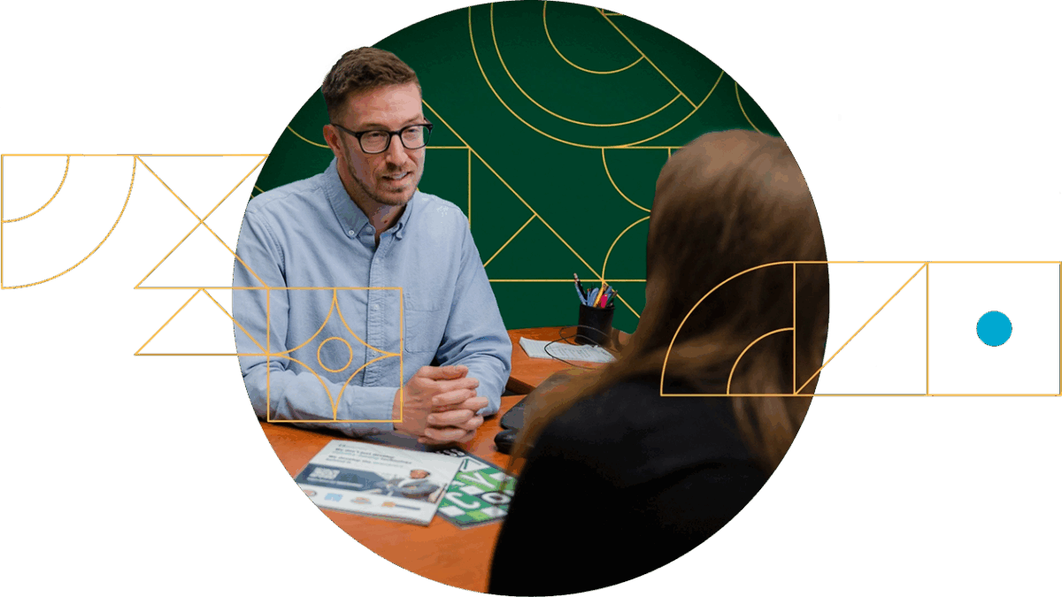 A Paycom Client Setup Representative with glasses and blue shirt speaks with client partner.